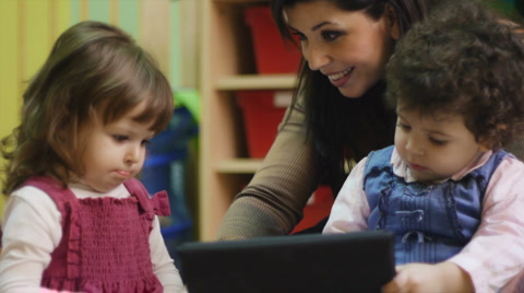 Teacher using tablet pc with children at school