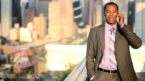 African American manager using mobile on rooftop Manhattan business office 