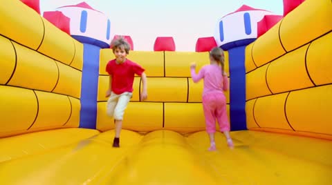 Pair of children boy and girl jump at inflatable playground