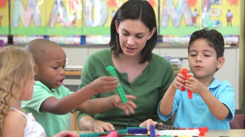 Teacher Sits With Group Of Children Using Construction Kit