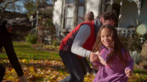 Happy mixed race family playing in autumn leaves