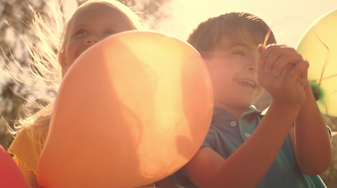 Five children playing in park with balloons.