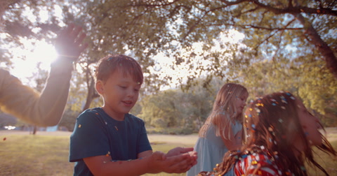 Slow motion kids having fun with confetti in a park