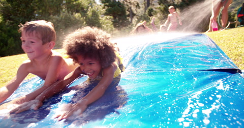 Afro girl and friends playing on a water slide