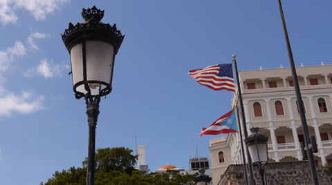 Old classical street ligh pole with USA and Puerto Rico flags in the background.