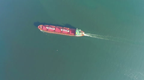 AERIAL, trade ship in the sea. Flying above ship in the ocean, waves in front.