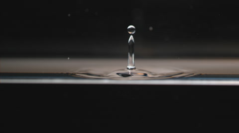 Slow motion macro, water drop falls, splashing and creating concentric ripples