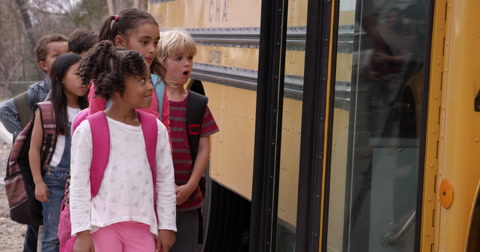 Young elementary school kids boarding a school bus