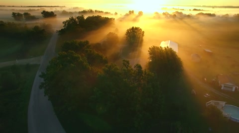 Breathtaking flight toward sunrise over foggy rural landscape