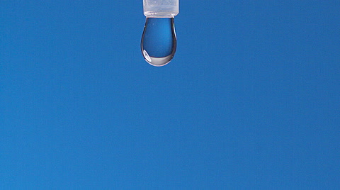 Drop of Water falling against Blue background, Slow motion