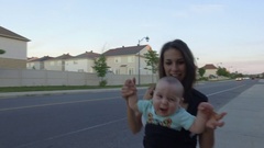 young mom dances with infant son down suburban street [45023832] | 写真素材・ストックフォトのアフロ