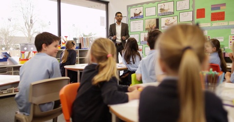 4K Elementary school children listening attentively to the teacher in classroom