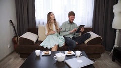 Couple is sitting on the couch sofa at home Look into the tablet … [44408502] | 写真素材・ストックフォトのアフロ
