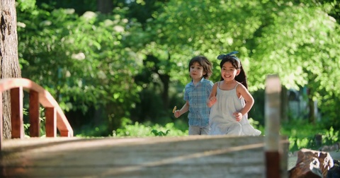 two children,a Caucasian boy and Asian girl running in the Park ,slow motion