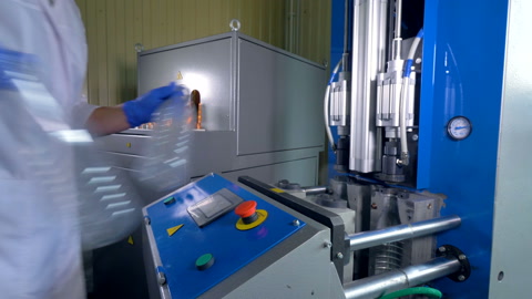 A worker in a lab coat makes preforms into large PET bottles.