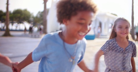 Multi-ethnic adopted family children on summer holidays running holding hands