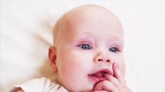 Baby boy sucks or chewes his small fingers looking at someone … [137975217] | 写真素材・ストックフォトのアフロ
