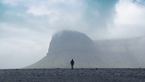 Aerial Flight Over Lonely Brave Man Figure Walking to Nordic Mountain Landscape