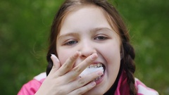 Teenager girl eating cotton candy on a stick and Hamming [137734765] | 写真素材・ストックフォトのアフロ