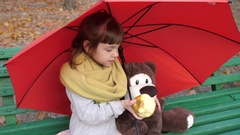 little girl and toy friend sit on a bench in park under an … [136419272] | 写真素材・ストックフォトのアフロ 
