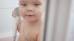 Baby boy a shower with play water in bathroom. [132673919] | 写真素材・ストックフォトのアフロ