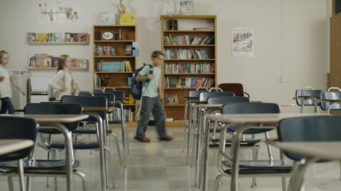 Panning shot of children arriving for start of class in elementary school