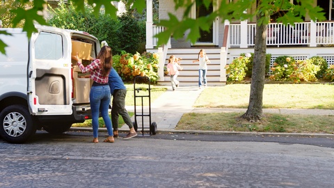 Children Helping Unload Boxes From Van On Family Moving In Day