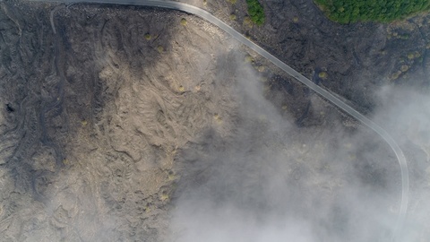 Aerial top down view of volcanic landscape first showing thick clouds 4k