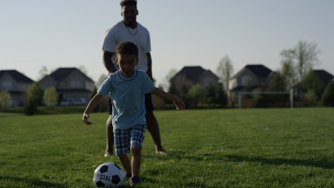 Kids playing soccer with their dad