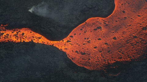 Aerial view river of volcanic lava flowing seaward