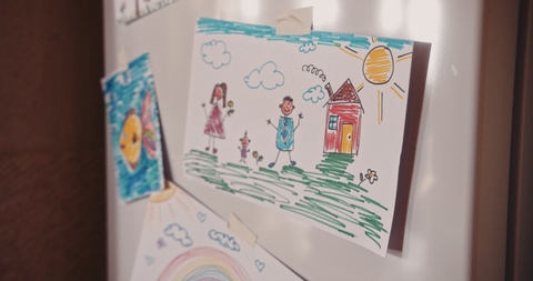 Children's colorful drawings on refrigerator door in family house kitchen