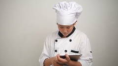 Asian preteen boy in Japanese chef uniform using tablet [132285336] | 写真素材・ストックフォトのアフロ