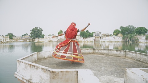 young Indian woman in colorful costume performing classical dance on a fort