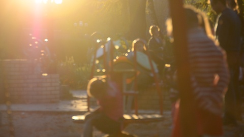 Kids on playground in the park against sunset. Soft focus.