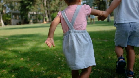 Little children running to parents in summer park