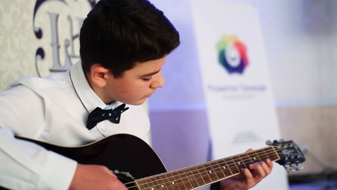 Close up adult young man playing a classical guitar sitting outdoors casual