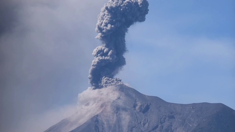 Tall volcanic eruption with blue grey skies Fuego Volcano Guatemala 1080p