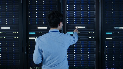 In the Modern Data Center: IT Engineer Standing Beside Open Server Rack Cabinet