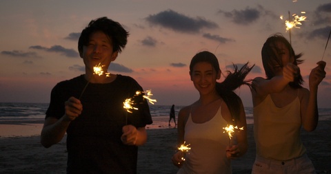 Young teenagers partying on the beach with fireworks.