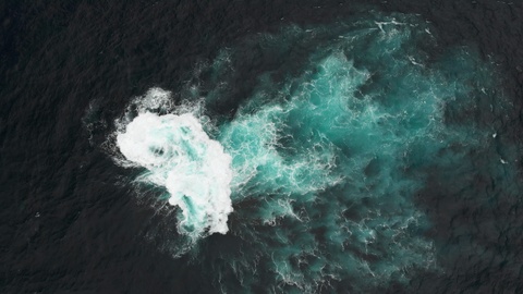 Aerial shot. Volcanic stone reef in the waters of the ocean. Waves hit him to