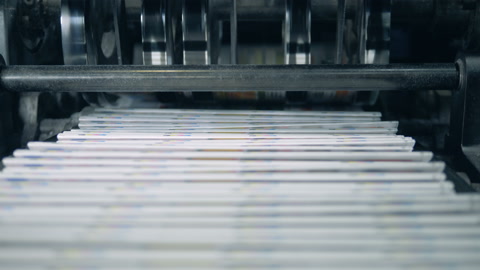 Stacked newspaper on automated conveyor, typography facility.