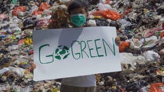 Preteen boy shows a text of Go Green at landfill [133361300] | 写真素材・ストックフォトのアフロ