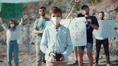 Cheerful teen boy in protective mask showing young plant staying … [133001619] | 写真素材・ストックフォトのアフロ