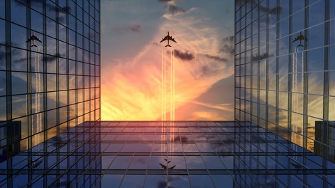 Airplane Flies Over Business Skyscrapers Against Sunset Clouds