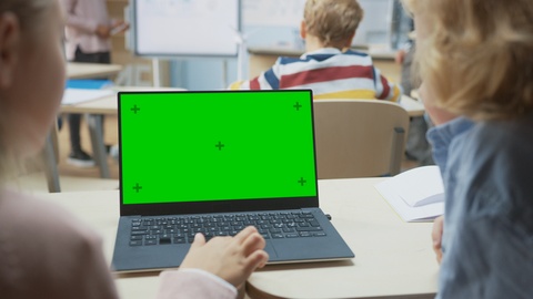 Elementary School Classroom: Two Kids Using Green Mock-up Screen Laptop in Class