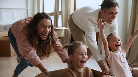 Parents and children homeowners playing with boxes on moving day