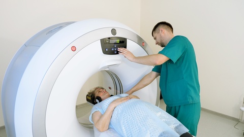 Radiologist controls CT or MRI or PET scan with elderly female patient. 4K