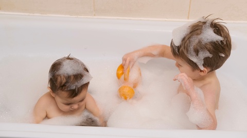 Happy little kids brothers playing together in the bath