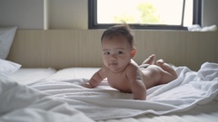 prone baby naked is smile while lying on the bed [128622853] | 写真素材・ストックフォトのアフロ 