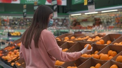 Young beautiful girl in a medical mask chooses oranges [128544445] | 写真素材・ストックフォトのアフロ